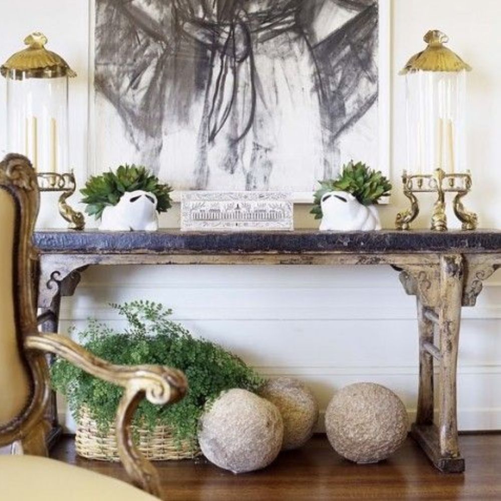 Rustic console table with gold lanterns, succulents, and decorative spheres in French country style