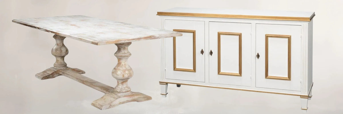 Distressed white farmhouse dining table with turned legs beside white sideboard with gold trim