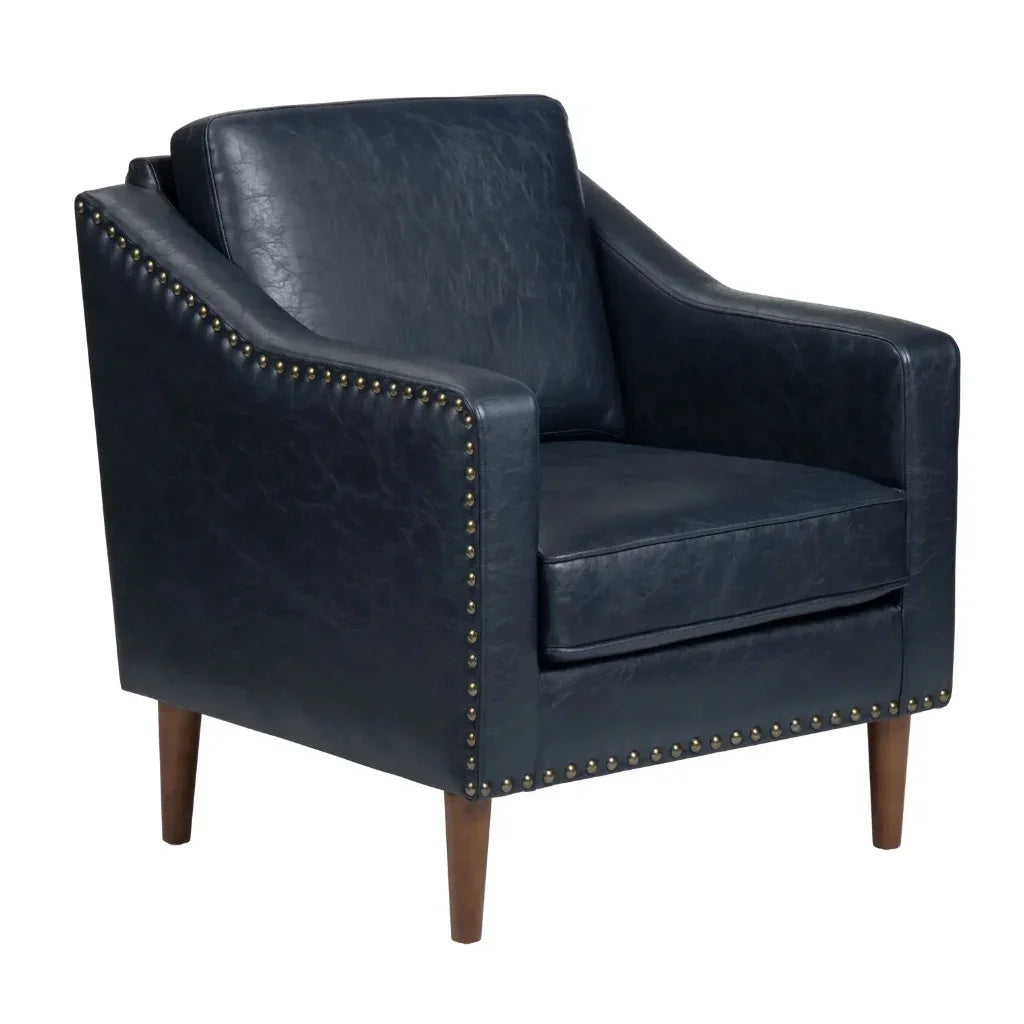 Navy blue faux leather armchair with gold nailhead trim and wooden legs in a modern farmhouse style.