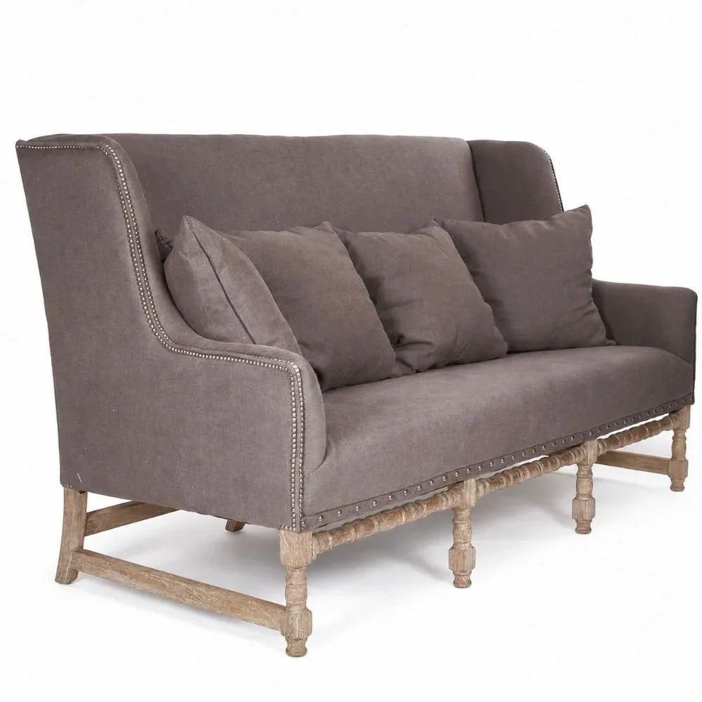 French country sofa with nailhead trim, rustic wood legs, and plush cushions in taupe fabric