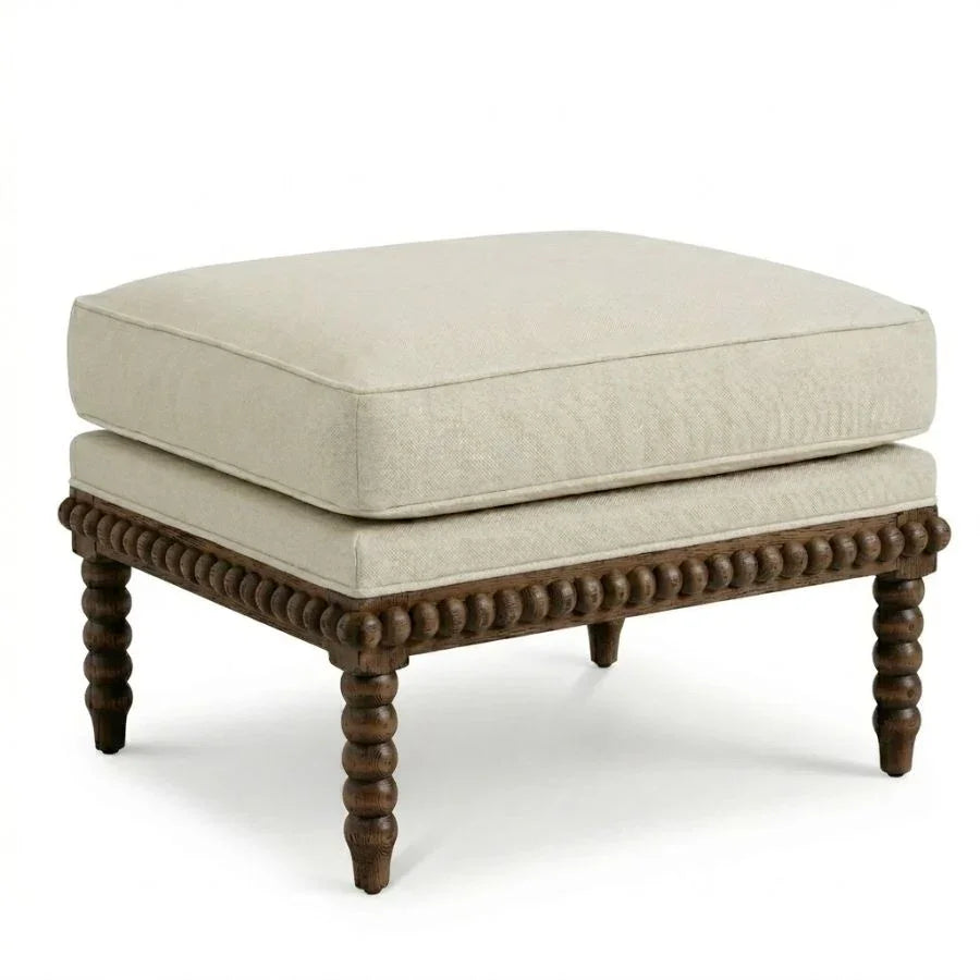 Beige cushioned ottoman with dark wood bead detailing and turned legs, French country style