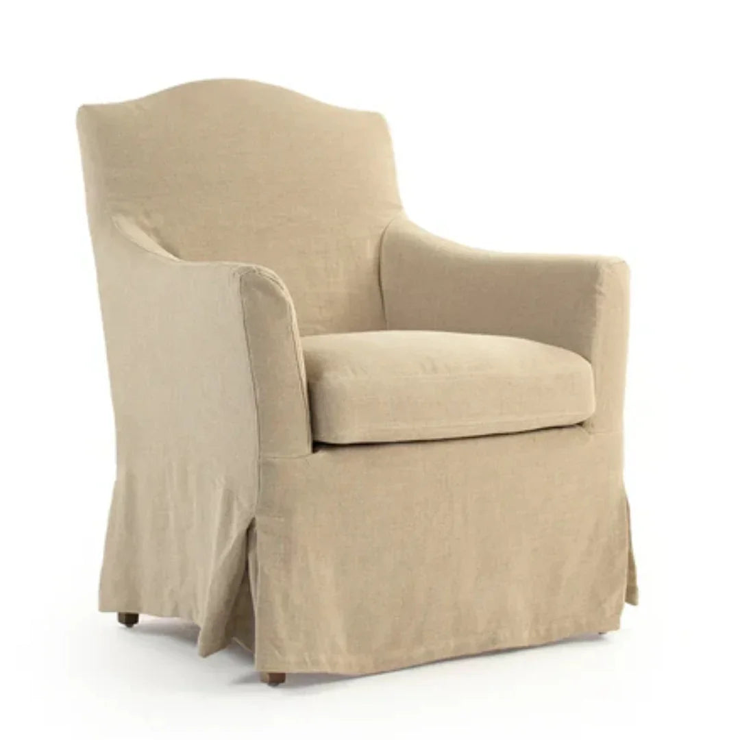 Beige slipcovered armchair with curved back and skirted base, ideal for French country or farmhouse decor