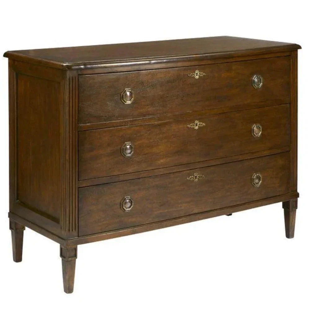 Rustic wooden dresser with three drawers, ornate brass handles, and tapered legs in farmhouse style