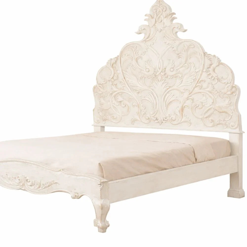 Elegant white shabby chic bed with ornate carved headboard and vintage farmhouse style