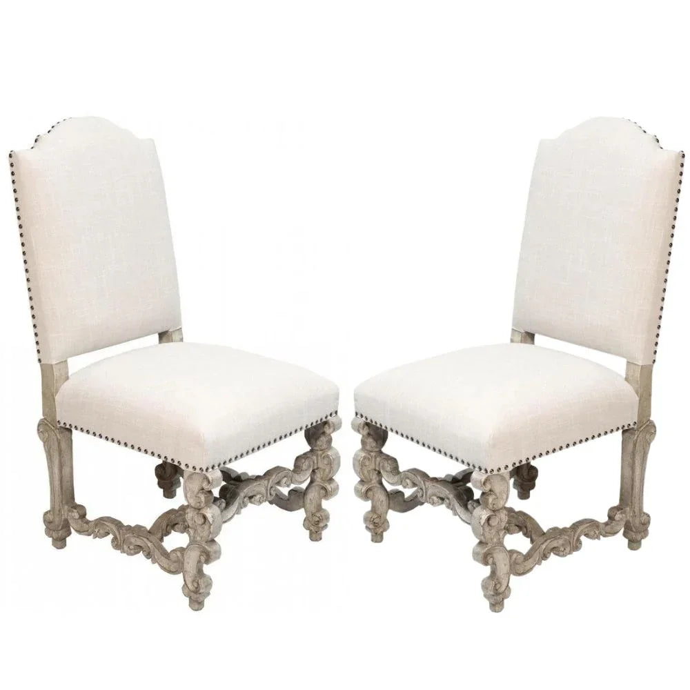 Elegant French country dining chairs with ornate carved legs and nailhead trim, upholstered in neutral fabric.