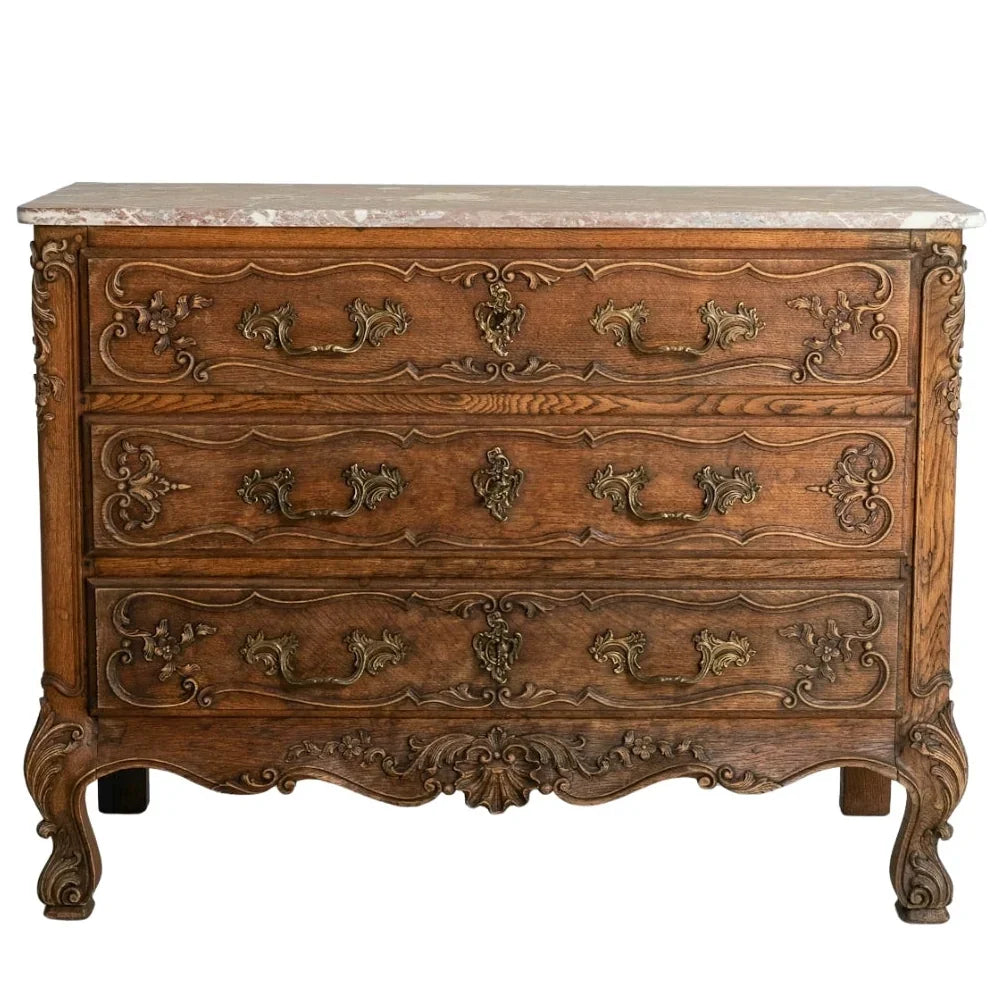 Antique French country three-drawer oak commode with marble top and ornate carvings.