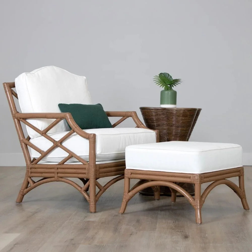 Natural rattan armchair and ottoman with white cushions and a green accent pillow.
