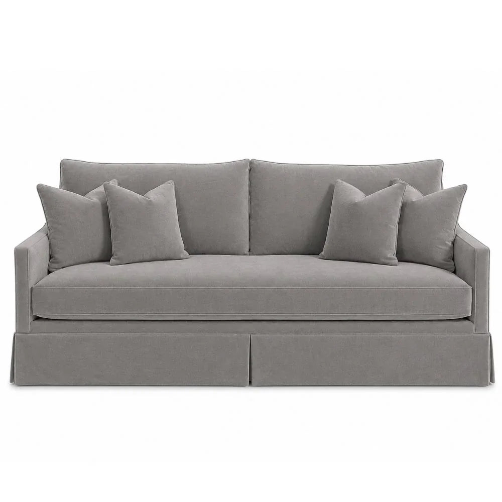 Grey velvet slipcovered sofa with matching throw pillows in a classic farmhouse style.