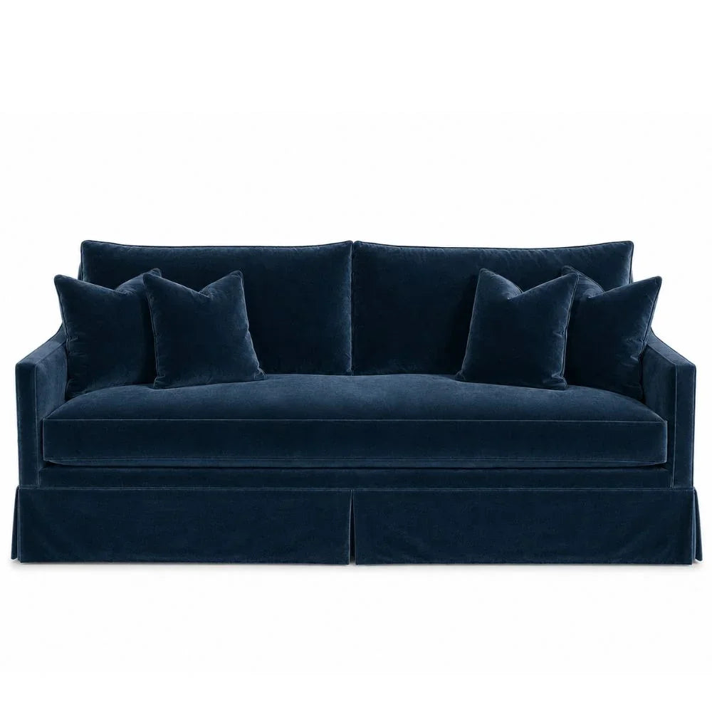 Navy blue velvet sofa with matching throw pillows in a classic style.