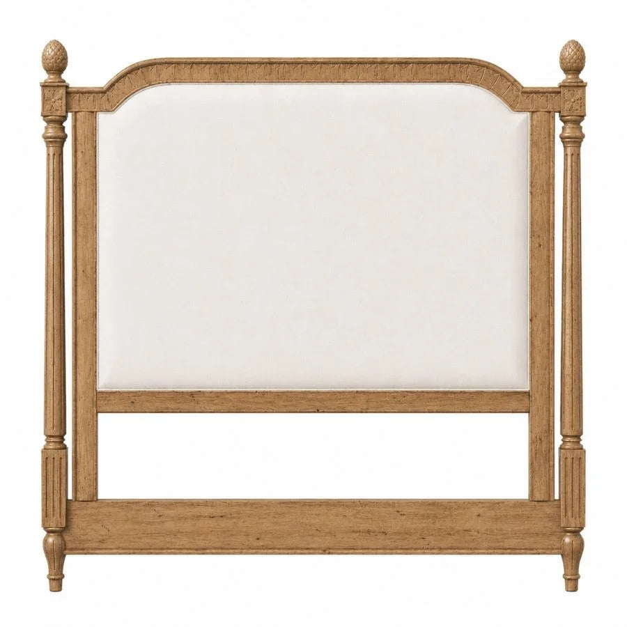 French country style wooden headboard with a cream upholstered panel and ornate posts.
