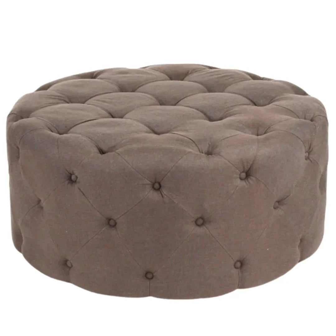 Tufted round ottoman in taupe fabric with deep button detailing, French country style.
