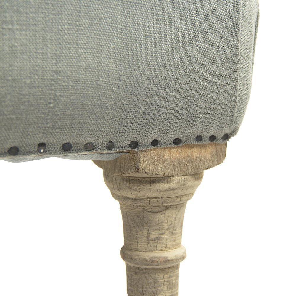 Grey linen upholstered chair with nailhead trim and distressed wood leg, farmhouse style