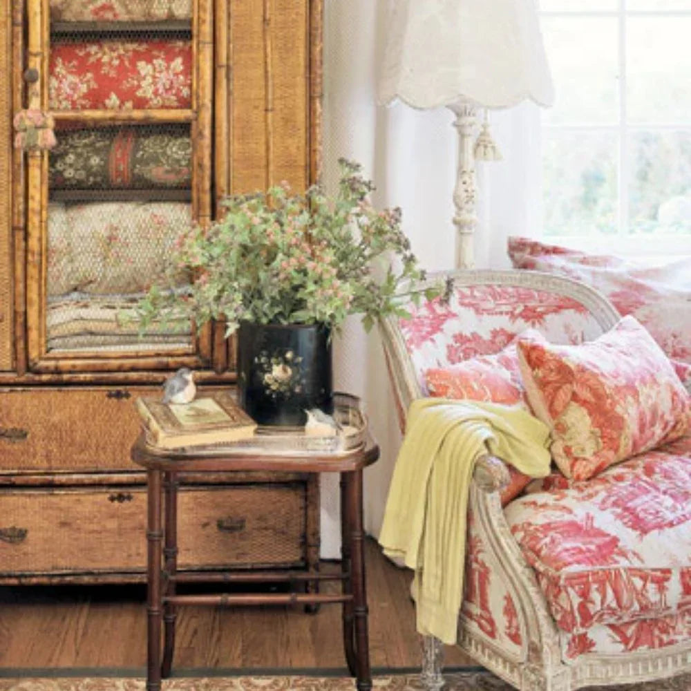 Shabby chic armchair with red toile print, vintage bamboo cabinet, and rustic side table in cozy farmhouse living room