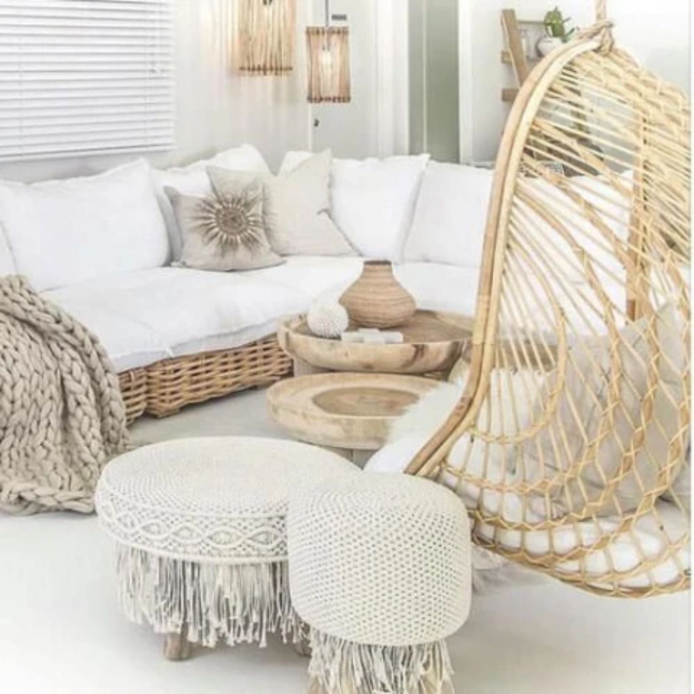 Natural boho living room with wicker sofa, macrame ottomans, and rattan hanging chair