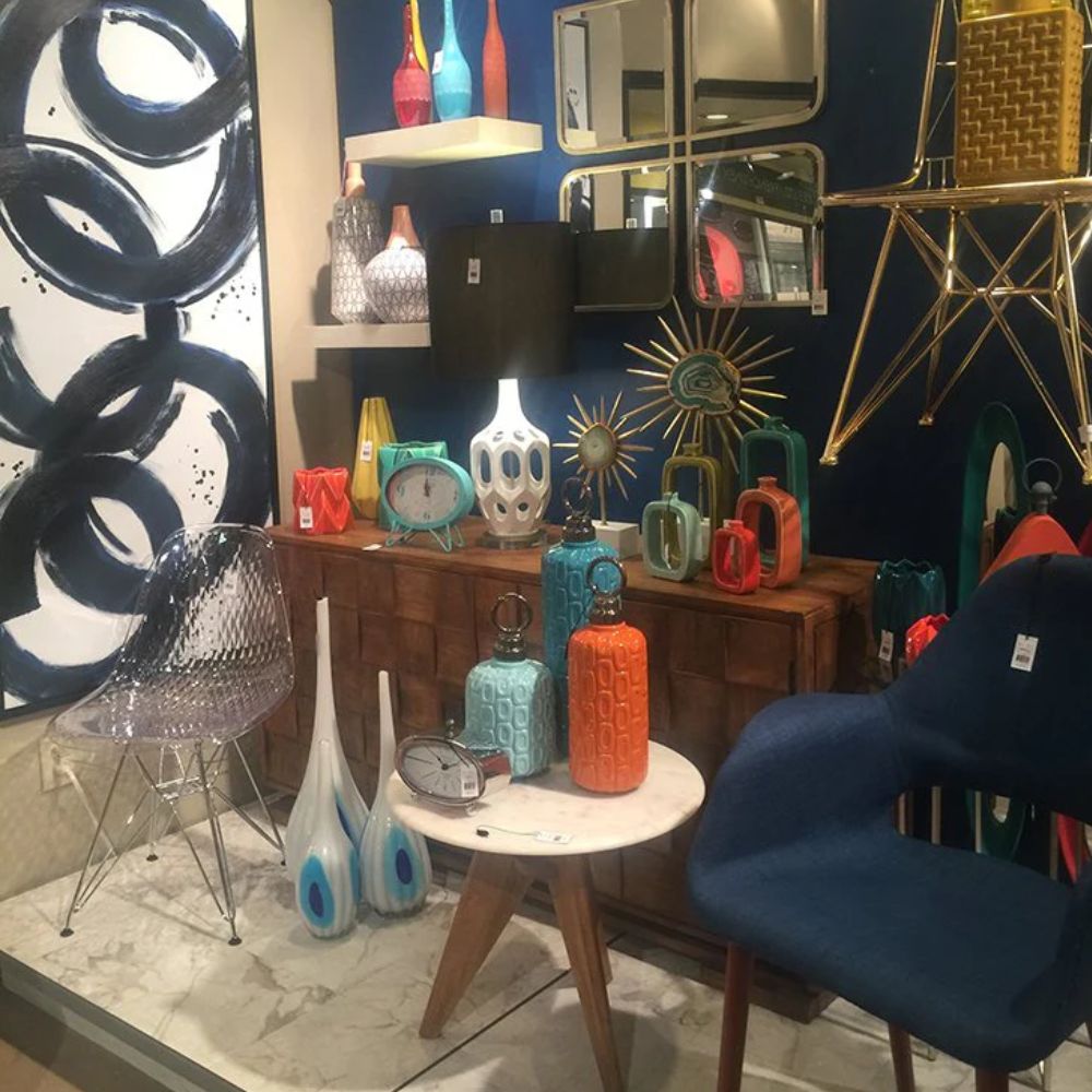 Coastal and boho home decor with colorful vases, modern chairs, and art on navy wall