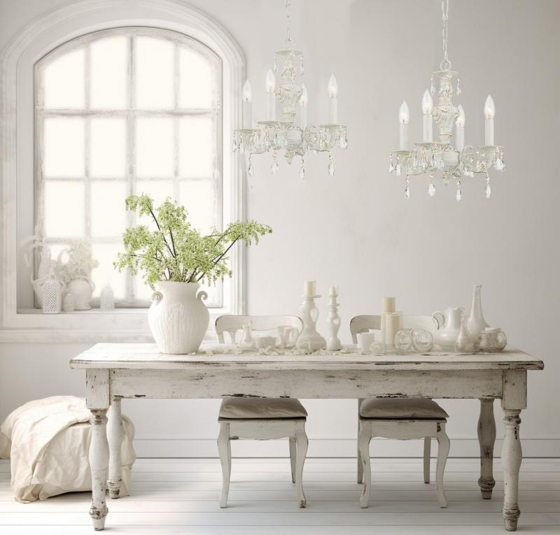 Shabby chic white dining table with crystal chandeliers, vintage chairs, and rustic decor in a bright farmhouse-style room