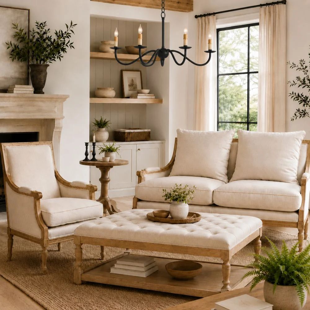 French country farmhouse living room with cream upholstered seating, tufted coffee table ottoman, rustic wood accents, and black iron chandelier
