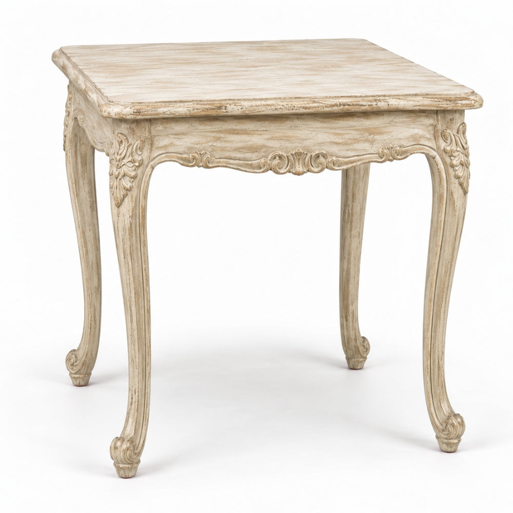 A square side table with a distressed, weathered finish in a light beige/cream tone, featuring ornate carved details on the apron and cabriole-style legs, shown against a plain white background.