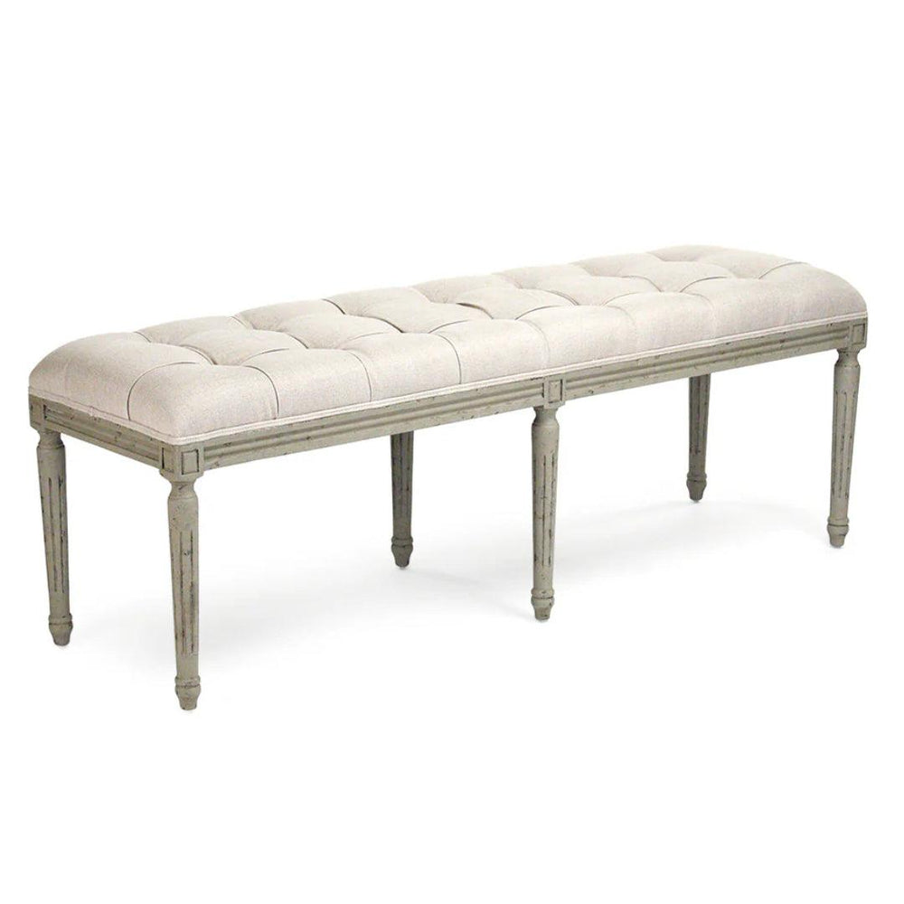 French country tufted bench with beige upholstery and weathered grey wooden legs.