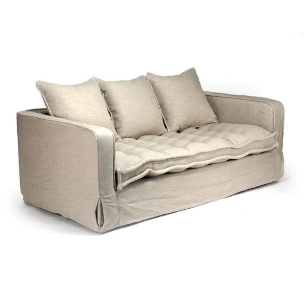 Neutral linen slipcovered sofa with tufted cushion and three pillows, farmhouse style
