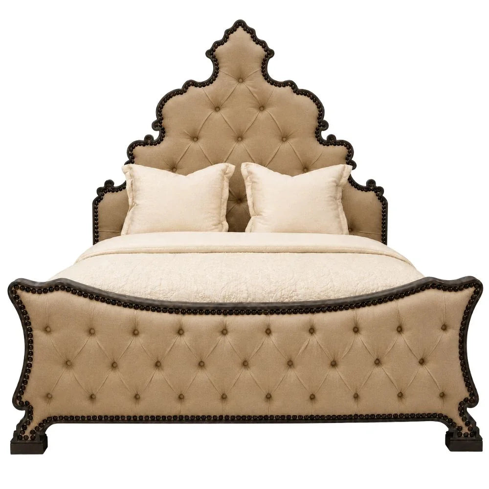 A luxury upholstered bed with a tall, scalloped tufted headboard and matching footboard, finished in beige fabric with dark wood trim and nailhead detailing, styled with cream bedding and pillows on a white background.