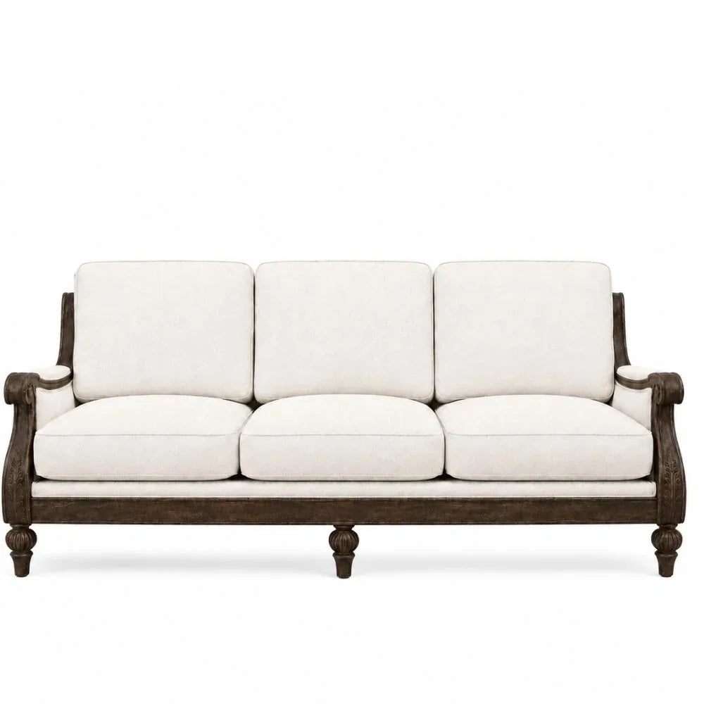 A three-seat sofa with cream-colored upholstered cushions and a dark brown wooden frame with turned legs and arm details, shown against a plain white background.